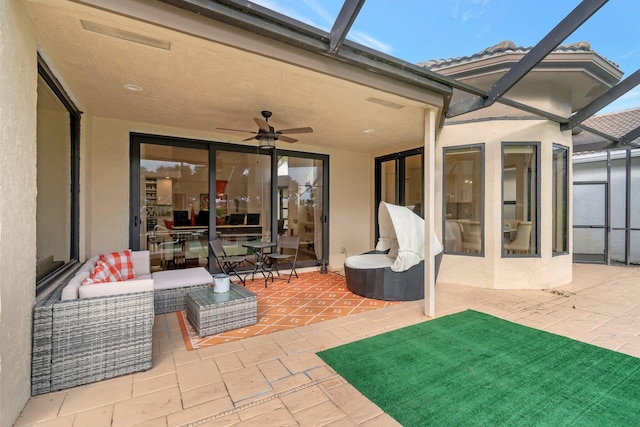 view of patio featuring an outdoor living space, glass enclosure, and ceiling fan