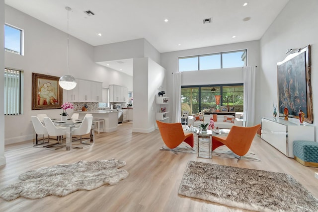 living room with a towering ceiling, light hardwood / wood-style floors, and plenty of natural light