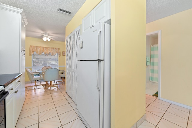 kitchen featuring white cabinets, white fridge, and light tile patterned flooring