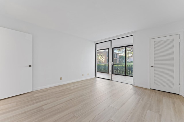 empty room featuring expansive windows and light hardwood / wood-style flooring