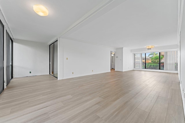 unfurnished living room with a wall of windows and light hardwood / wood-style flooring