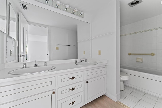 full bathroom featuring tiled shower / bath, vanity, and toilet