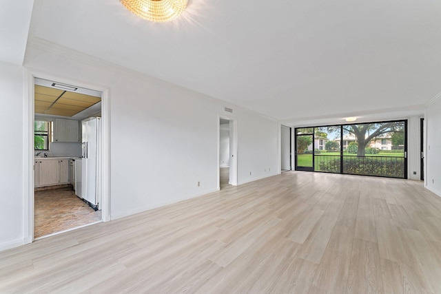 unfurnished living room with expansive windows, light hardwood / wood-style floors, crown molding, and a chandelier