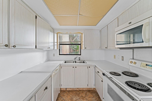 kitchen featuring sink, dark tile patterned floors, and white appliances