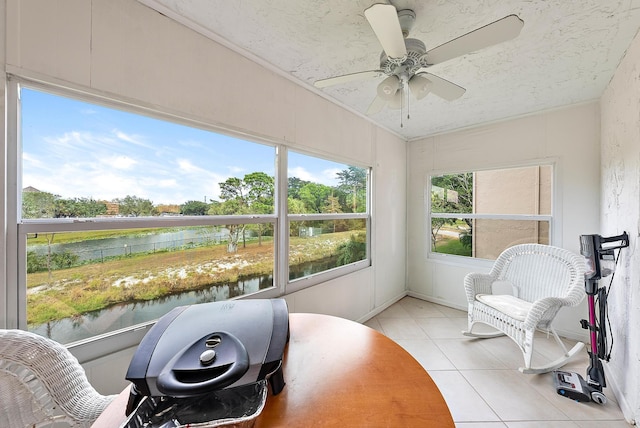 sunroom / solarium with ceiling fan and a water view