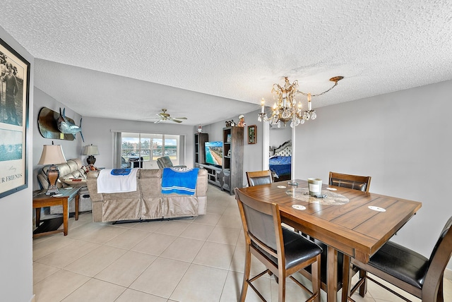 tiled dining space with a textured ceiling and ceiling fan with notable chandelier