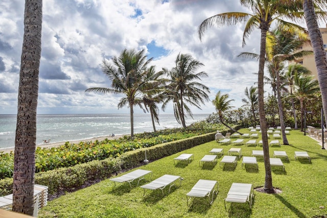 view of property's community with a water view, a view of the beach, and a yard