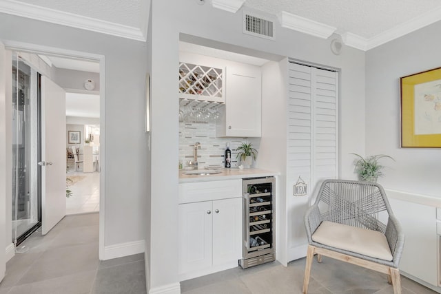 bar with wine cooler, indoor wet bar, crown molding, visible vents, and a sink