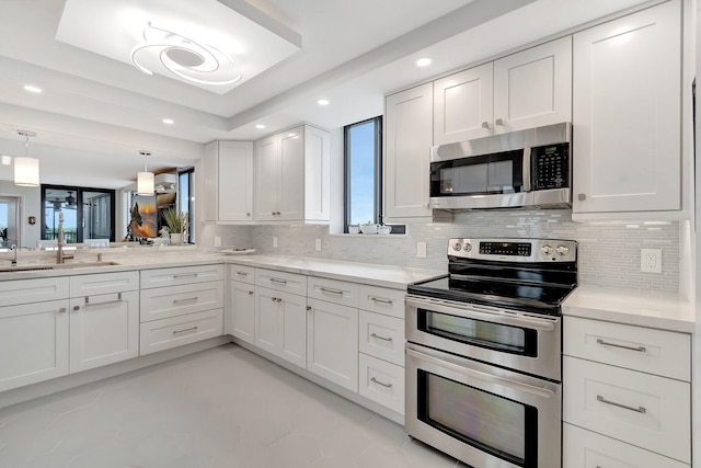 kitchen featuring recessed lighting, stainless steel appliances, a sink, white cabinetry, and tasteful backsplash