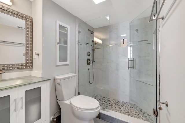 bathroom featuring toilet, a marble finish shower, and vanity