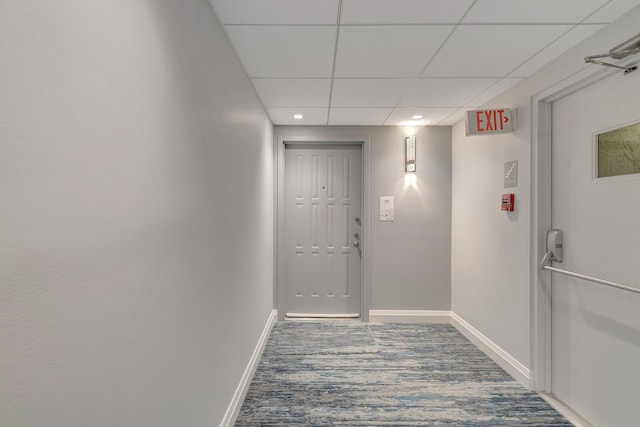 corridor with a drop ceiling and baseboards