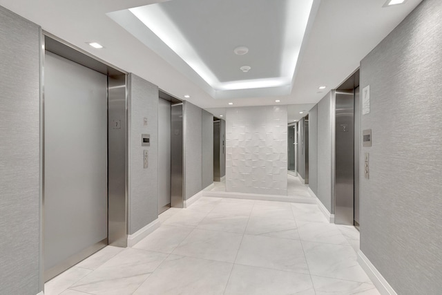 hall featuring elevator, a tray ceiling, and recessed lighting