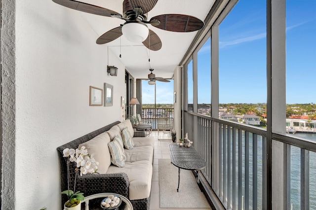 sunroom with a ceiling fan and a water view