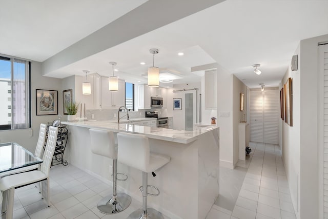 kitchen featuring light tile patterned floors, stainless steel appliances, a breakfast bar, a peninsula, and white cabinets