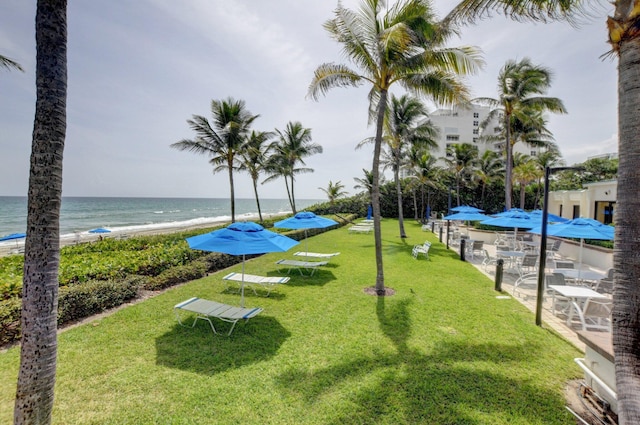 view of home's community with a lawn, a water view, and a view of the beach