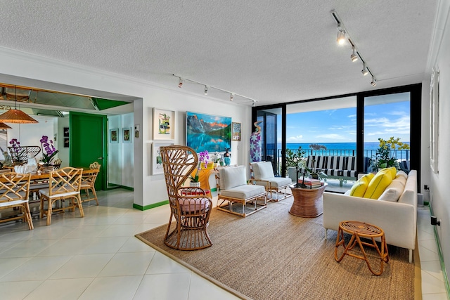 tiled living room featuring rail lighting, expansive windows, a water view, and a textured ceiling