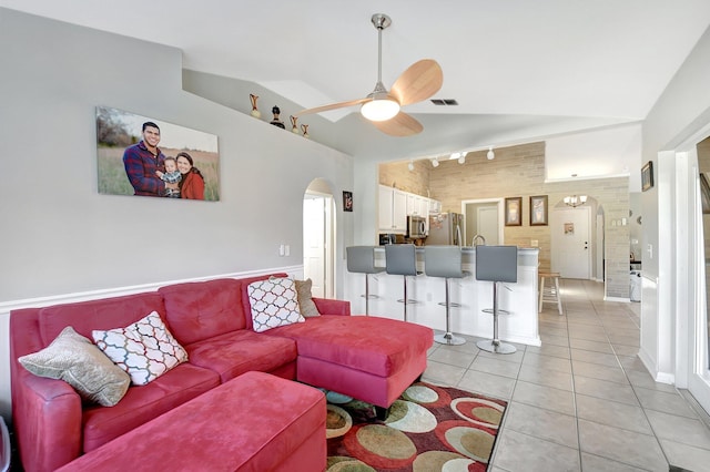 tiled living room featuring vaulted ceiling, ceiling fan, sink, and track lighting