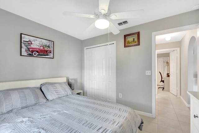 tiled bedroom with ceiling fan and a closet