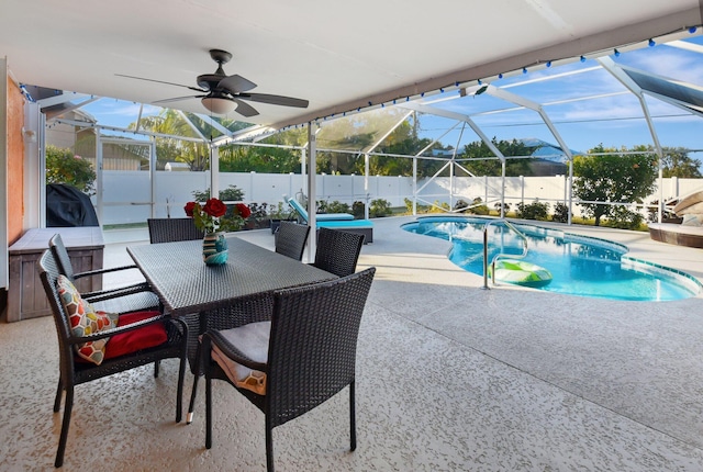 view of swimming pool featuring glass enclosure, ceiling fan, and a patio