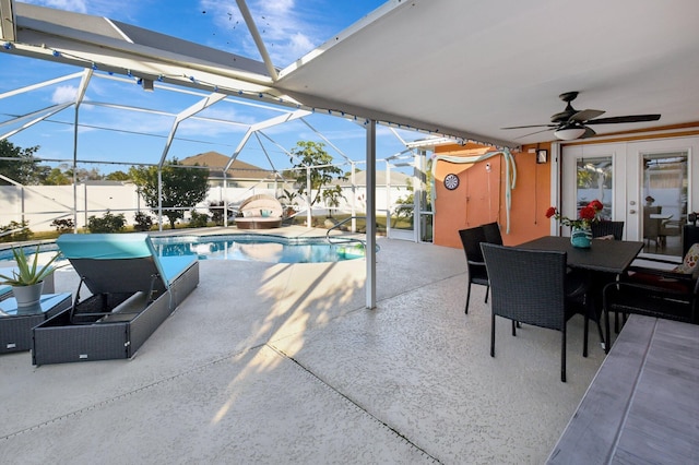 view of swimming pool with glass enclosure, ceiling fan, french doors, and a patio