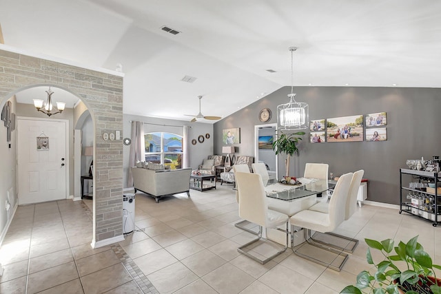 tiled dining space featuring ceiling fan with notable chandelier, vaulted ceiling, and ornate columns