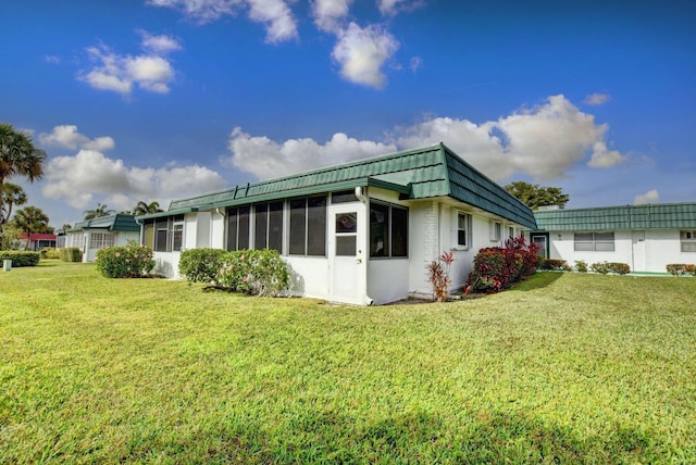 view of home's exterior with a sunroom and a lawn