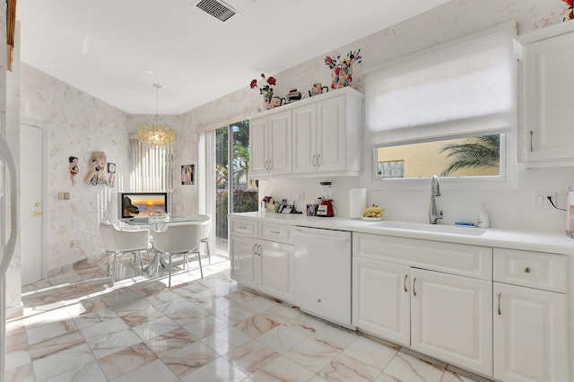 kitchen with dishwasher, sink, hanging light fixtures, a notable chandelier, and white cabinets