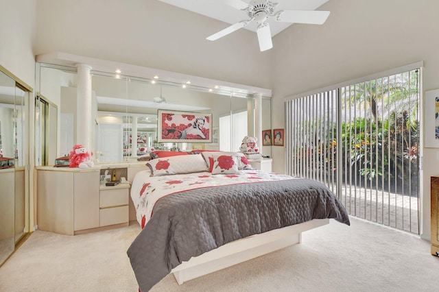 carpeted bedroom with access to exterior, a towering ceiling, and ceiling fan