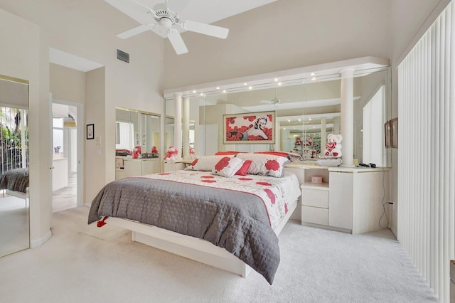 bedroom featuring ceiling fan, light colored carpet, and a high ceiling