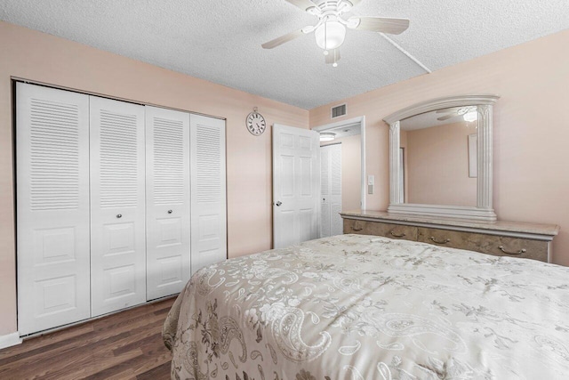 bedroom with ceiling fan, dark hardwood / wood-style floors, a textured ceiling, and a closet