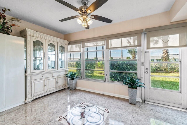 unfurnished sunroom featuring ceiling fan