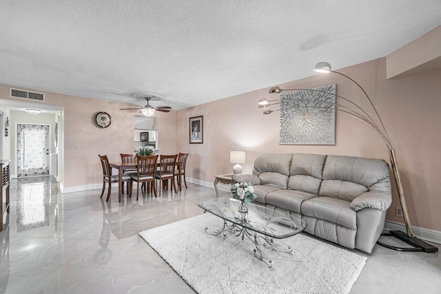 living room featuring ceiling fan and a textured ceiling