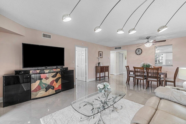 living room featuring ceiling fan and a textured ceiling