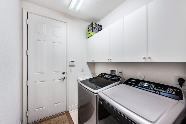 clothes washing area featuring cabinets, a textured ceiling, and washing machine and dryer