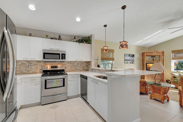 kitchen featuring sink, hanging light fixtures, kitchen peninsula, white cabinets, and appliances with stainless steel finishes