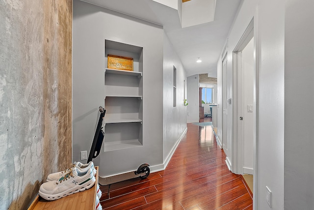 hall with built in features, baseboards, and wood finished floors