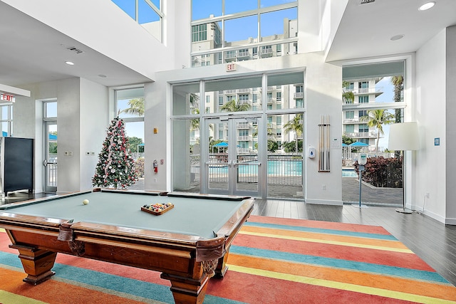 game room with hardwood / wood-style flooring and a towering ceiling