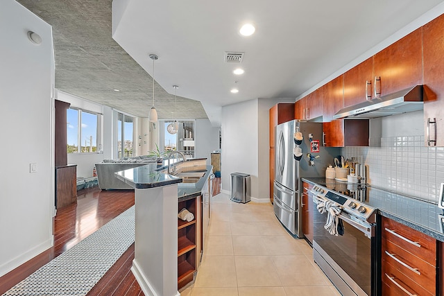 kitchen featuring decorative light fixtures, sink, backsplash, light tile patterned floors, and stainless steel appliances