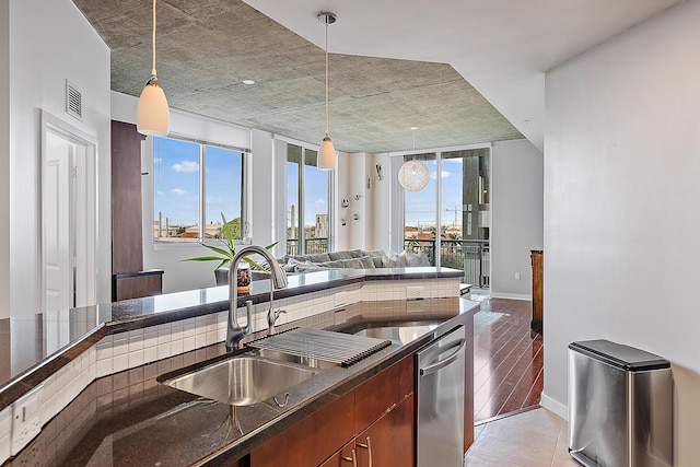 kitchen featuring stainless steel dishwasher, sink, a wealth of natural light, and decorative light fixtures