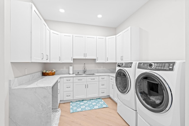 laundry room featuring cabinets, light hardwood / wood-style floors, washer and clothes dryer, and sink