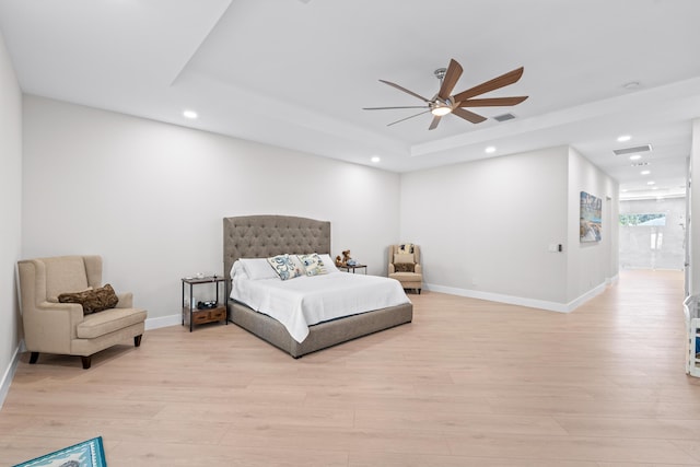 bedroom featuring ceiling fan, a raised ceiling, connected bathroom, and light hardwood / wood-style flooring