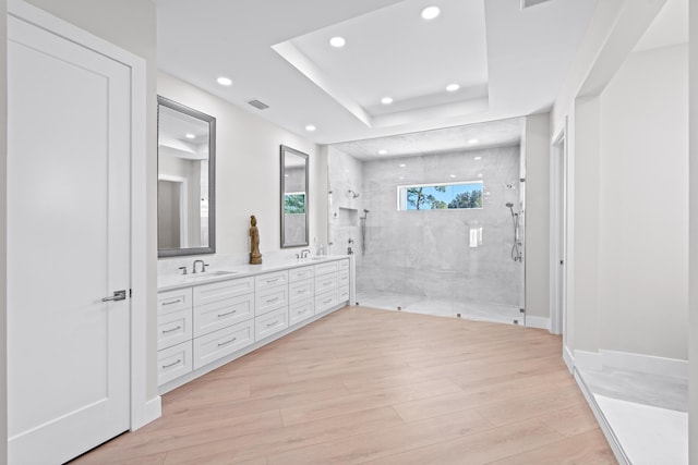 bathroom featuring a tile shower, a tray ceiling, vanity, and hardwood / wood-style flooring