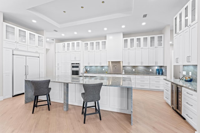 kitchen featuring wine cooler, a large island, white cabinets, and paneled built in fridge