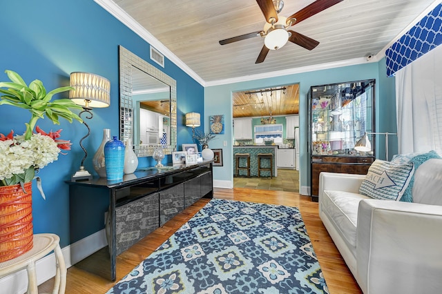 living area with light wood-type flooring, ornamental molding, and wood ceiling