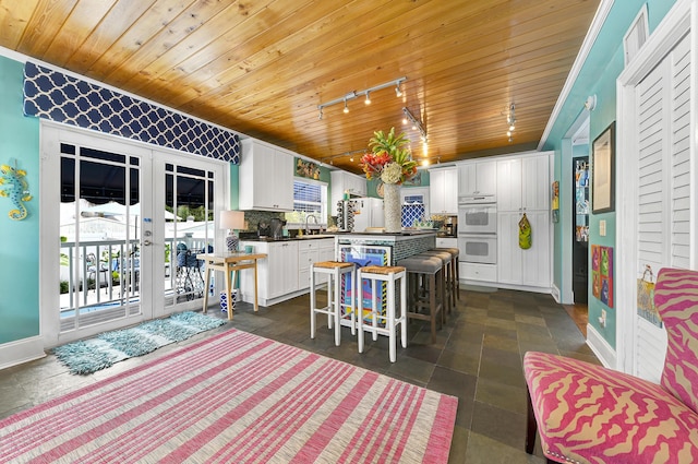 kitchen featuring white cabinetry, a center island, sink, a kitchen breakfast bar, and tasteful backsplash