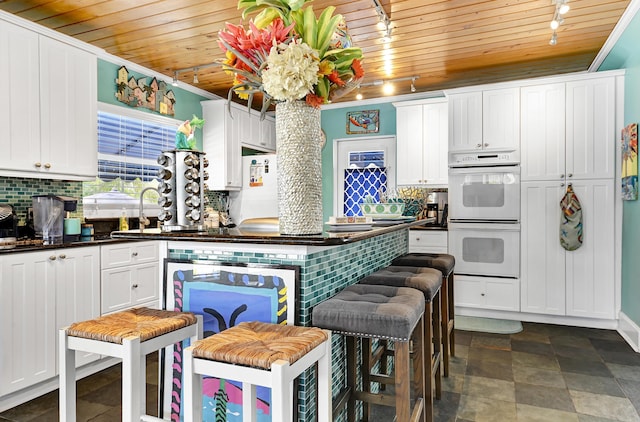 kitchen with tasteful backsplash, rail lighting, wooden ceiling, and white appliances