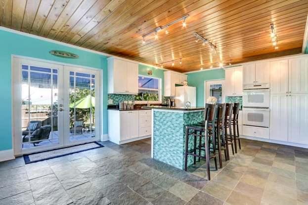 kitchen featuring french doors, white cabinets, wooden ceiling, and white appliances