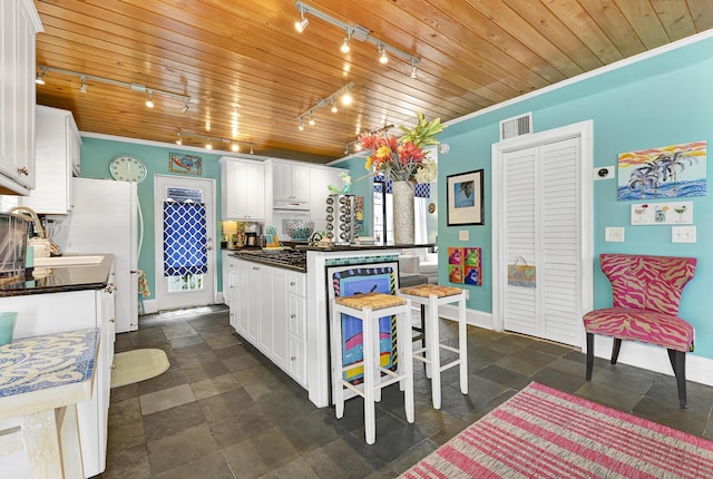 kitchen featuring a kitchen bar, rail lighting, wood ceiling, white cabinets, and a kitchen island