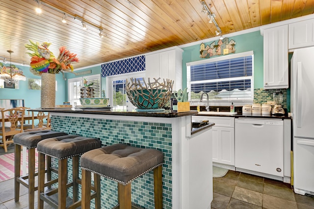 kitchen featuring white appliances, a kitchen bar, decorative backsplash, white cabinets, and wood ceiling