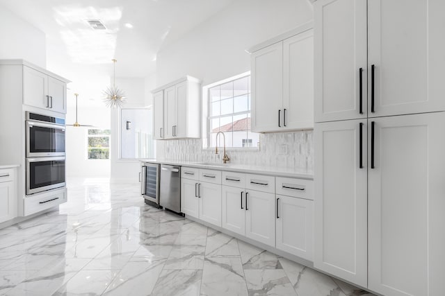 kitchen featuring a healthy amount of sunlight, white cabinetry, sink, and tasteful backsplash